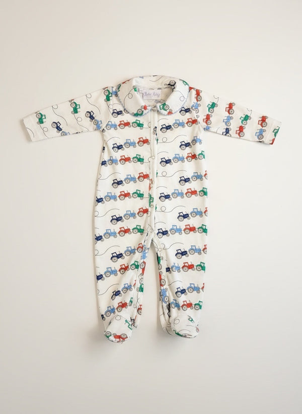 Rachel Riley for Bobbie's Shoppe white footed pajamas with all-over tractor print in red, blue, and green. Zipper closure.