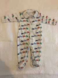 Bobbie's Shoppe white footed pajamas with all-over print of red, blue, and green tractors. Features a collar and zipper closure.